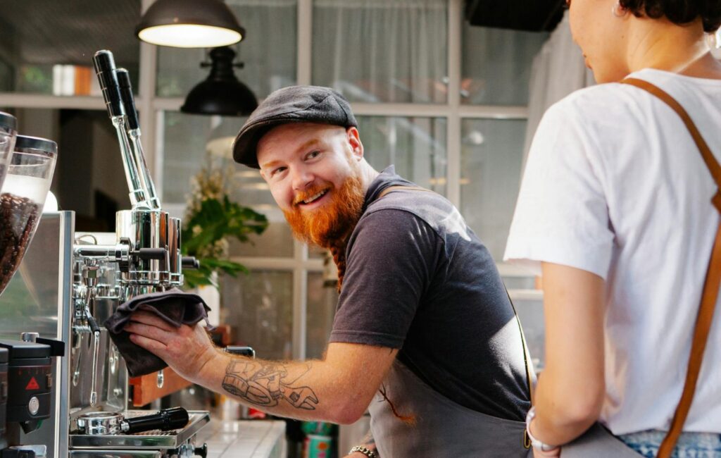 Barista at work smiling as they talk to a colleague